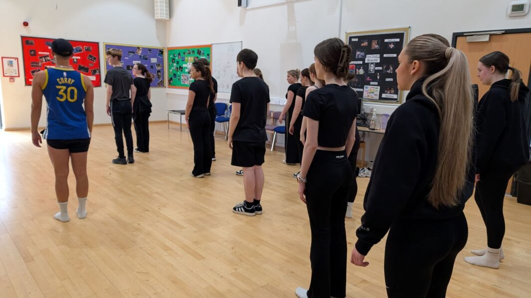 Male performer teaching class of students dance
