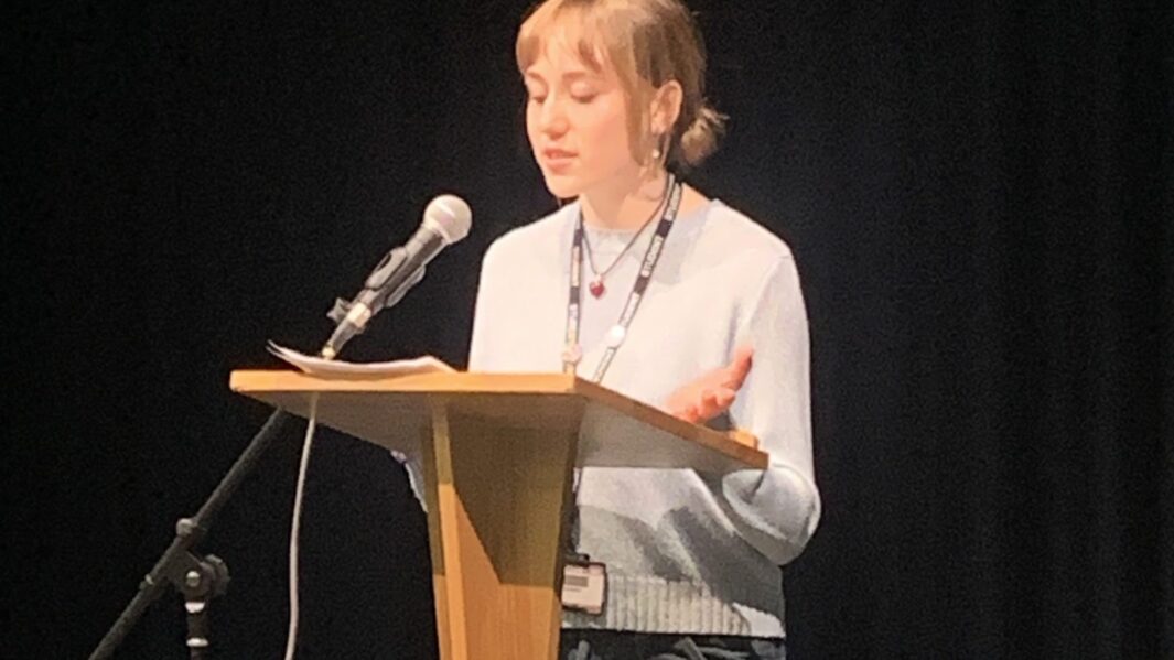 Female student stood behind lectern speaking