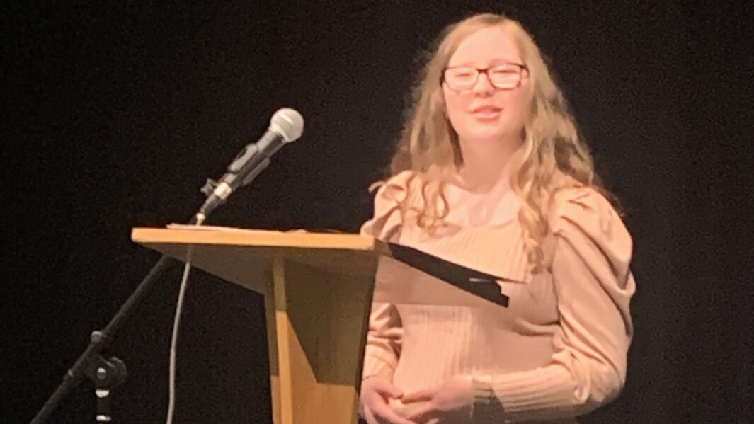 Female student stood behind lectern speaking