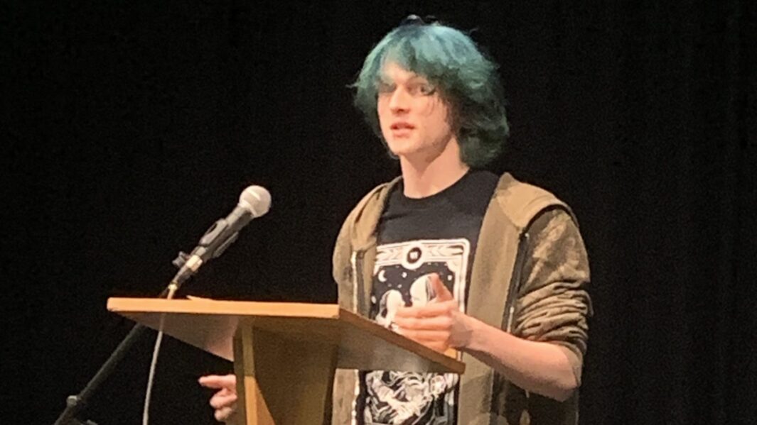 Male student stood behind lectern speaking