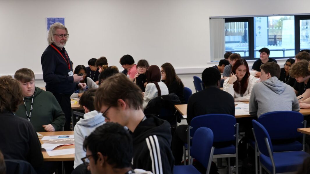 a large group of students sat in groups at tables in a Martin Bamber maths workshop