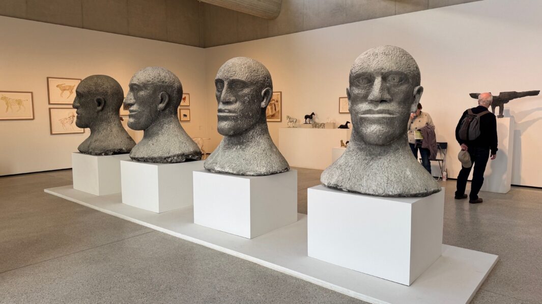 giant ceramic heads in a gallery, very serious faces