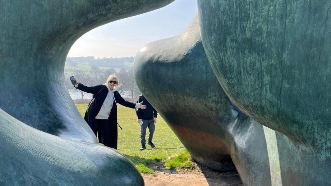 female teacher posing between a grey giant sculpture