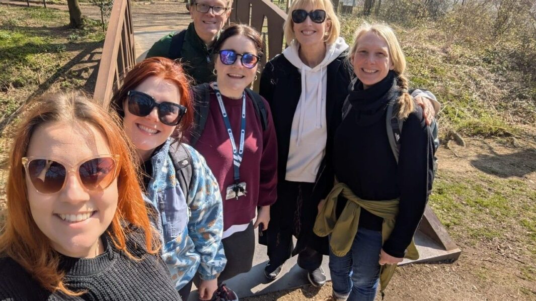 Five female and one male teacher posing for photo on a bridge