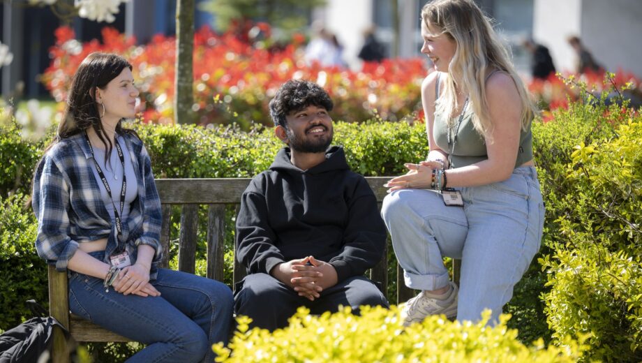 three students sat on a bench outside