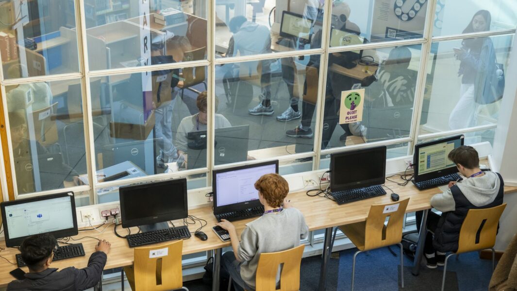 Student sat at computer in front of large glass window