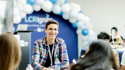 Male student sat at table smiling