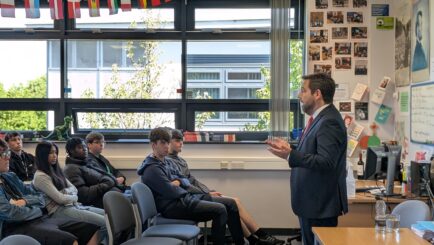 David Baines MP stood at the front of a school classroom talking to a room of students