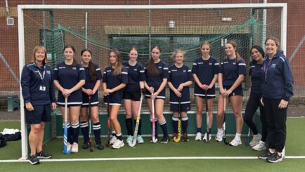 girls' hockey team photo with tutors on the ends