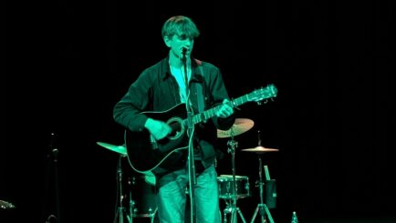 A male student playing the guitar in the Dalton Theatre at Carmel College