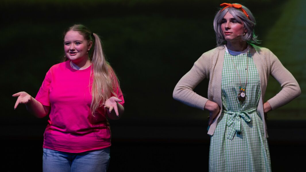 2 students on stage at the wizard of oz panto. I girls in a pink t short and 1 boy dressed as a woman