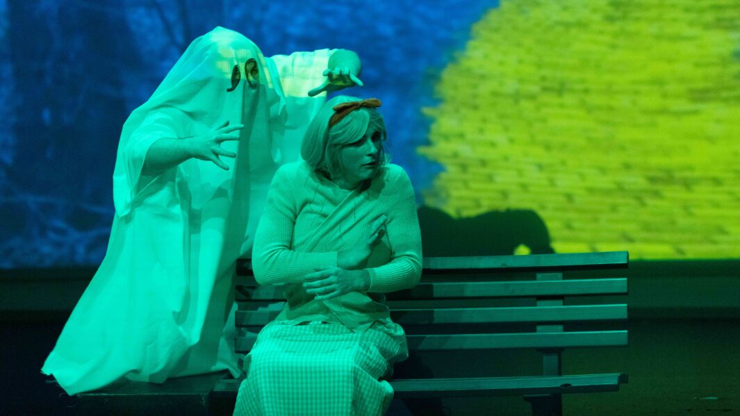 A student sat on a bench and another dressed as a ghost behind int he wizard of oz panto