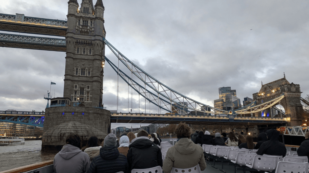 4 male students sat on a london river cruise near the London bridge