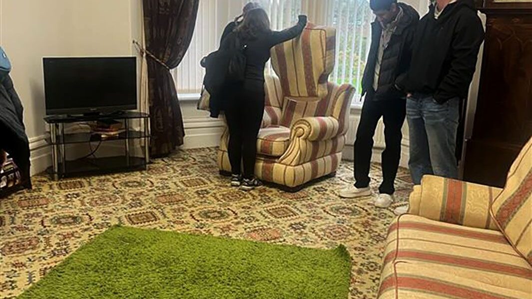 Carmel students search under armchair cushion as part of Edge Hill university's Crime Scene investigation experience.