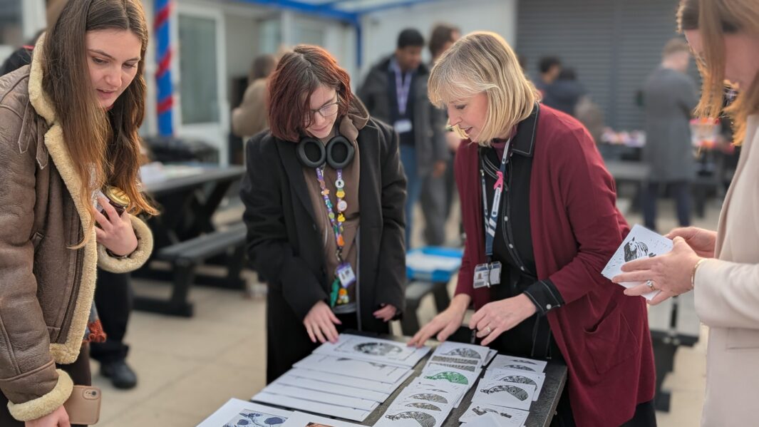 female staff members looking at a stall with printed artwork at the xmas market