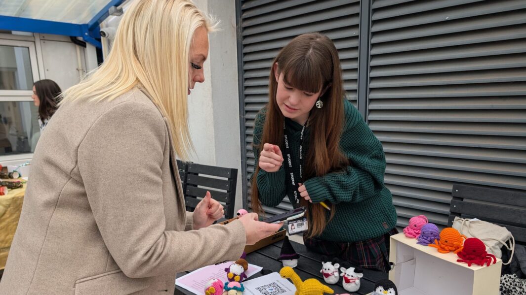 a female students and member of staff at a stall at the xmas market