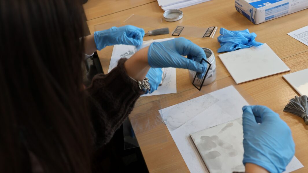 gloved hands of students working in the Criminology classroom looking at evidence