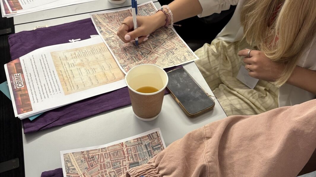 Image of students arms and hands doing work at a desk with coffee cups