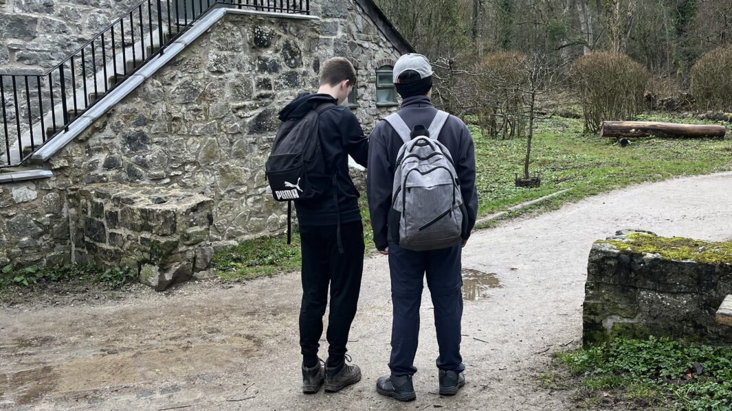 Two male students in a village in Wales reading a map ready for a walking expedition