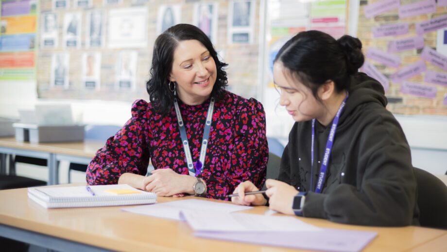 Photo of a female tutor and a male student sat at a desk