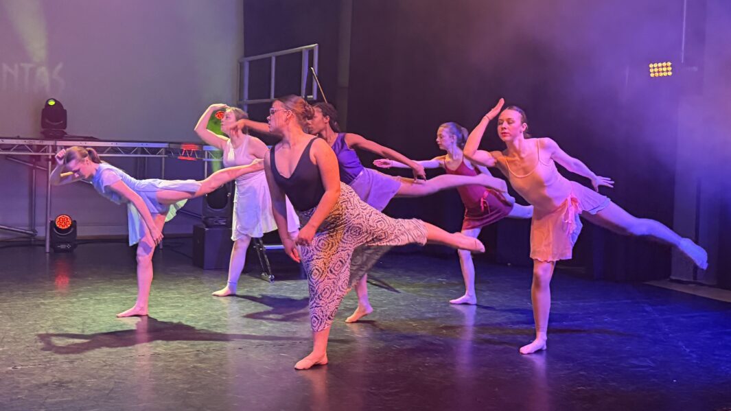 Girls on stage dancing and doing a standing leg extension