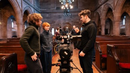 2 students using film equipment in a church hall