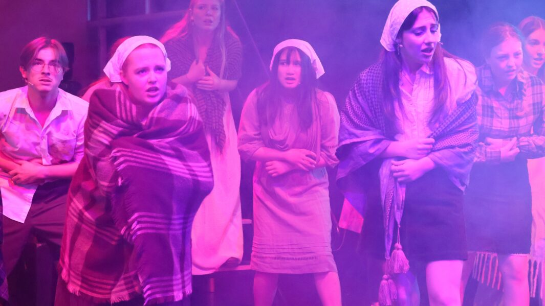 Group of students on stage wearing les mis costumes