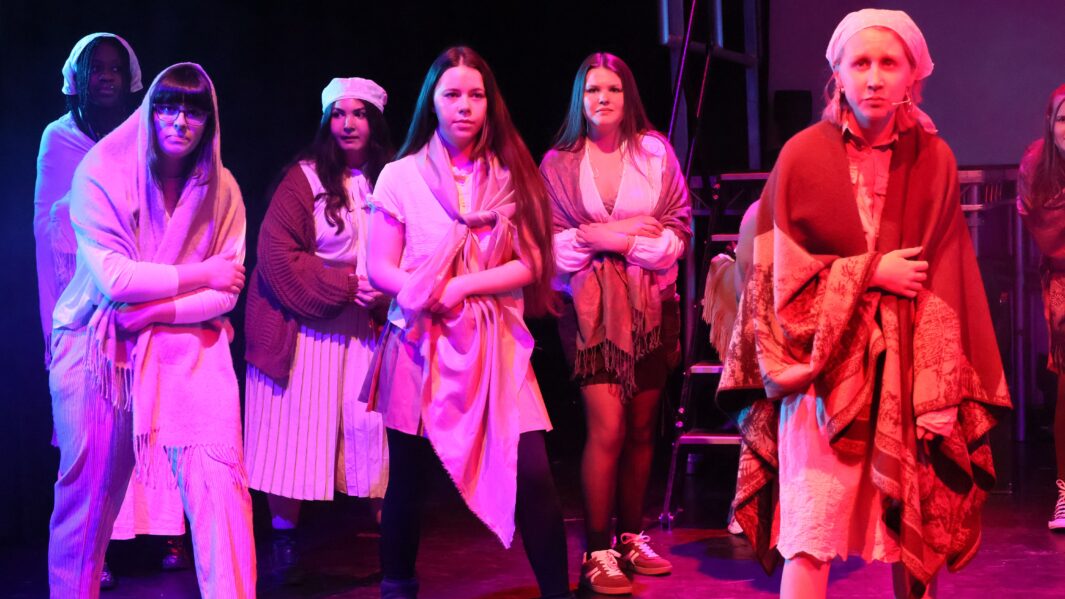Group of students on stage wearing les mis costumes