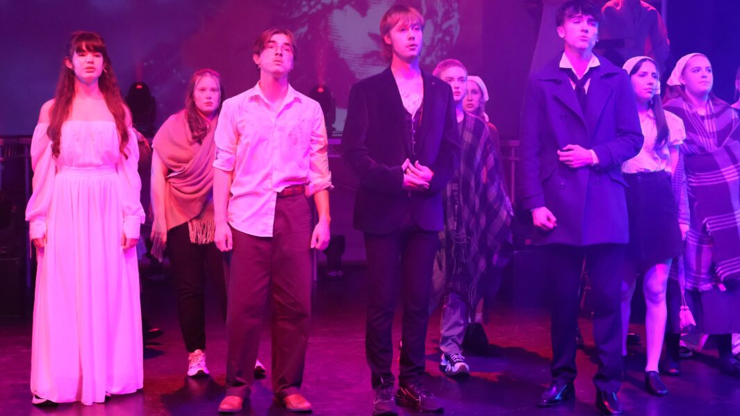 Large group of male and female students on stage singing
