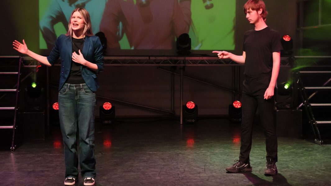 Boy and girl on stage wearing steet wear singing