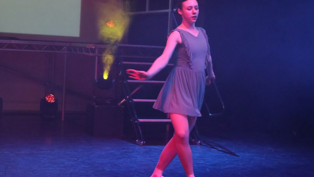 Girl on stage dancing wearing a blue flowy dress