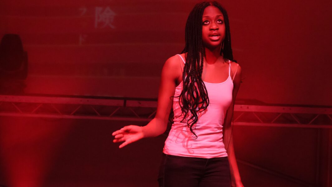 Girl on stage singing with red lighting on her