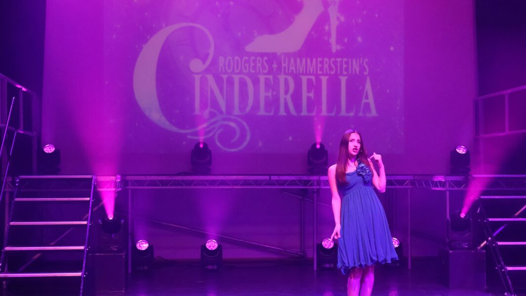 Girl on stage singing with a Cinderella backdrop
