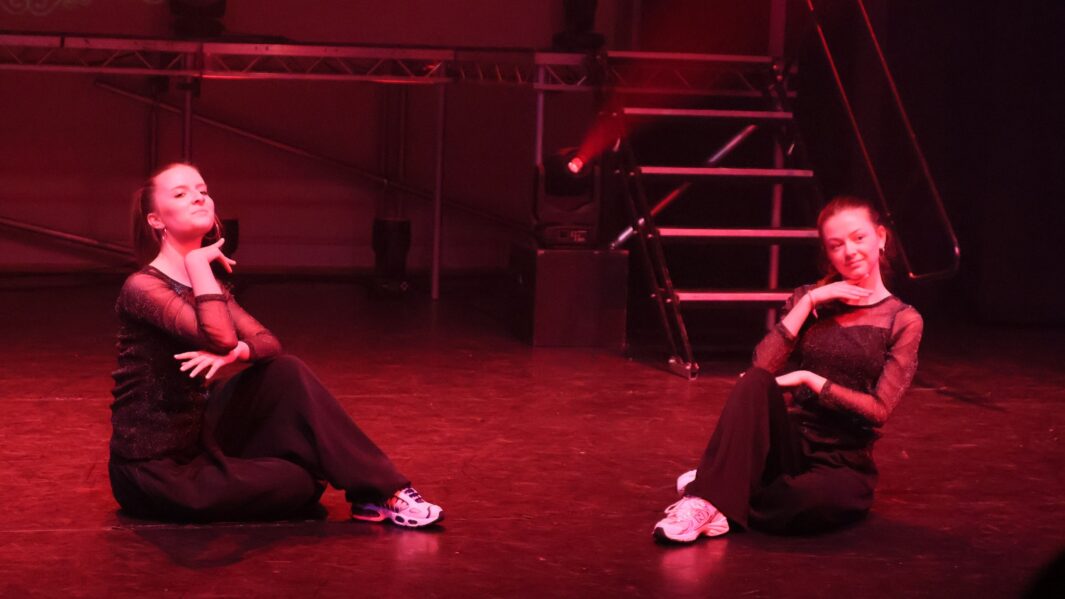 2 girls dancing on stage sat down