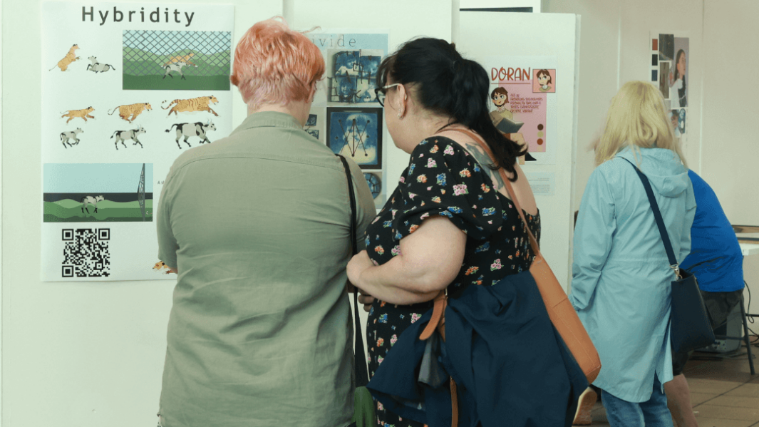 three women looking at artwork on exhibition display boards
