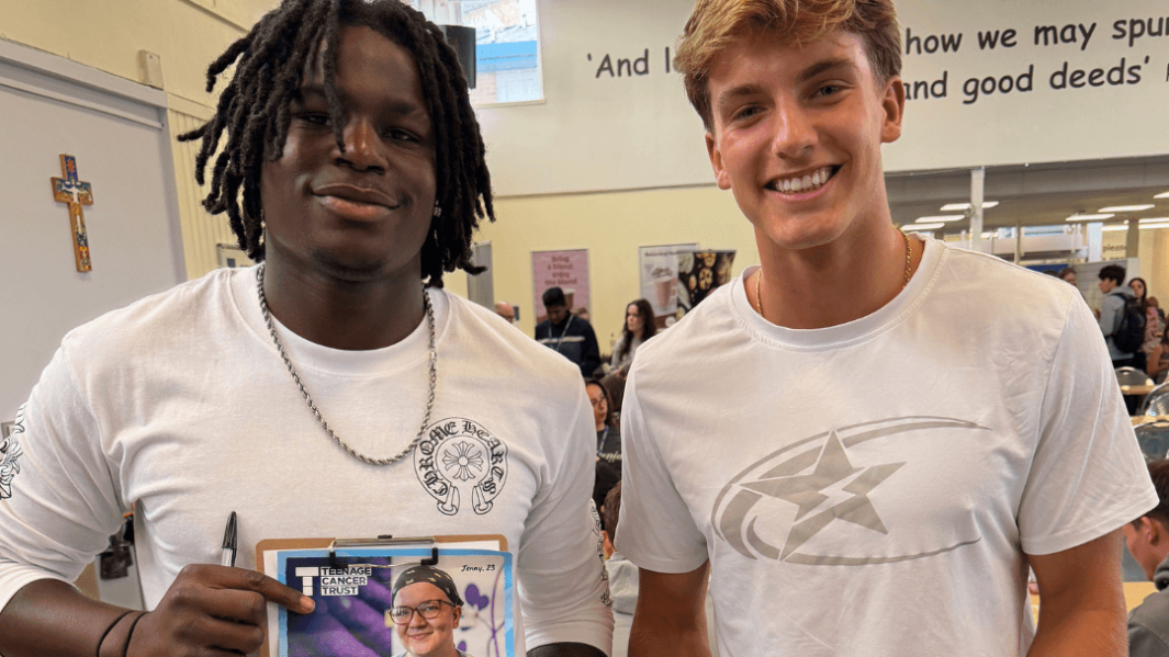 two male students smiling selling raffle tickets and baked goods