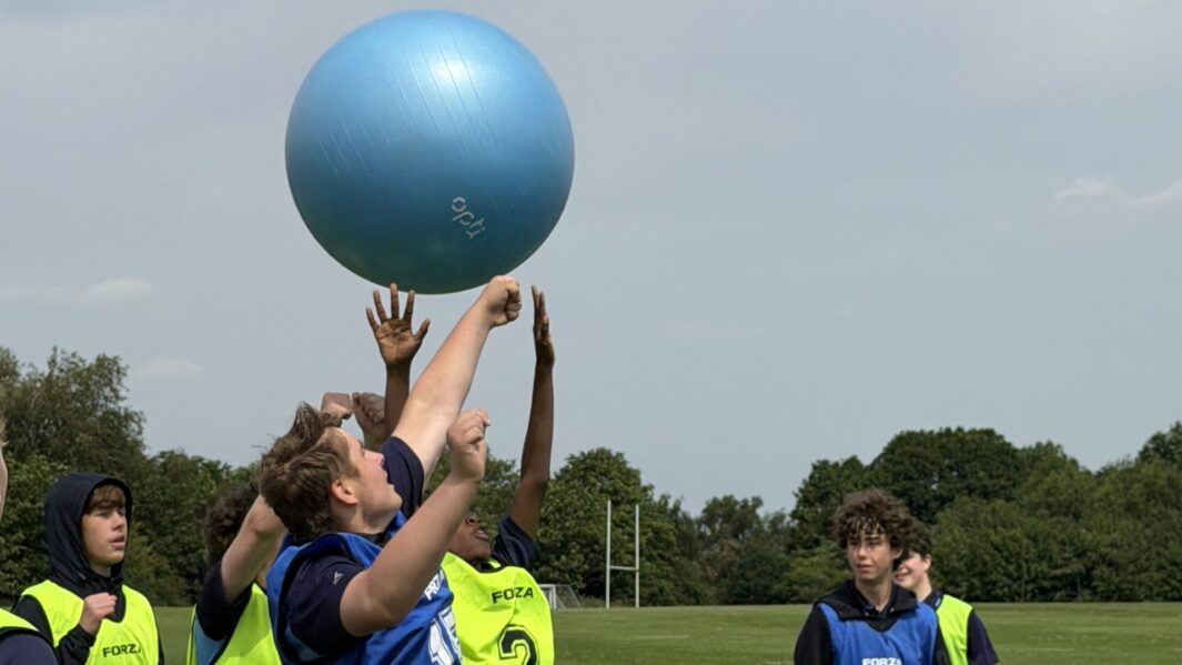students in sports bibs with a large bouncy ball