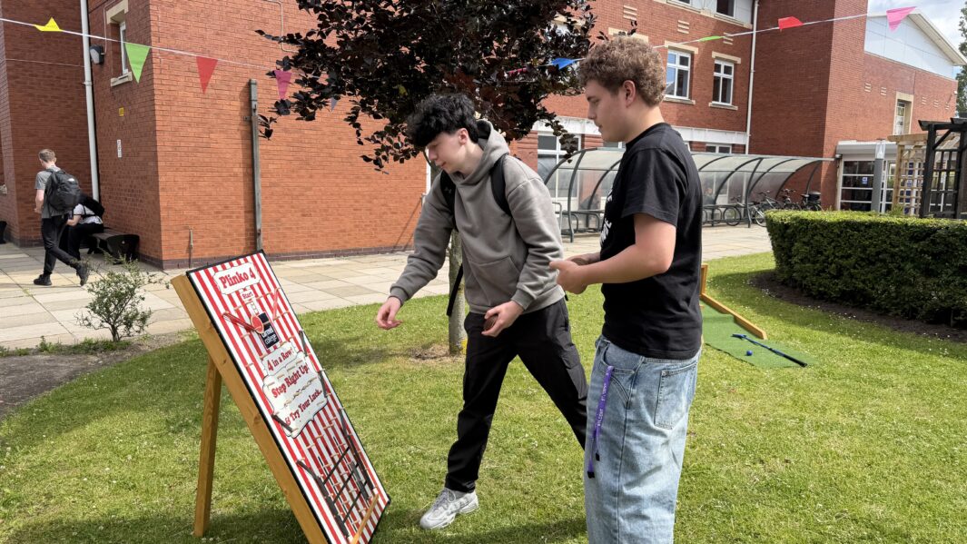 Two boys playing carnival games outside at Carmel College