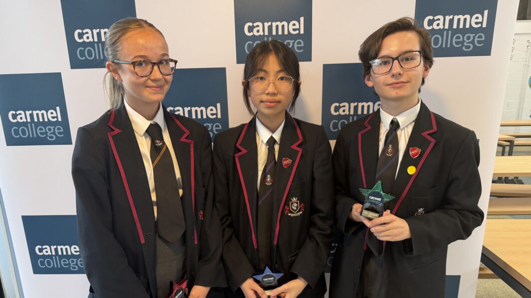 students in black school uniform stood holding trophies