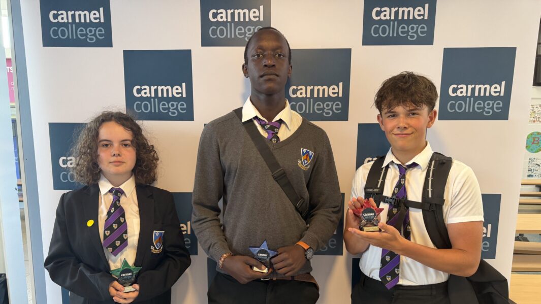 students in school uniform stood holding trophies