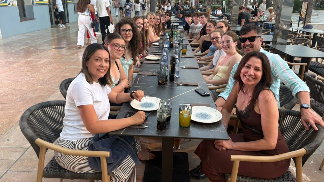 A large group of staff and students sat at a long restaurant table in Spain