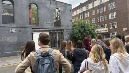 group of students looking up at a building, on a guided tour round east london