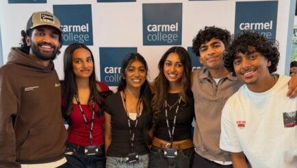 Students in front of the logos at the leavers celebration