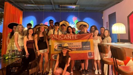A group of students in Alicante holding up a work experience flag banner