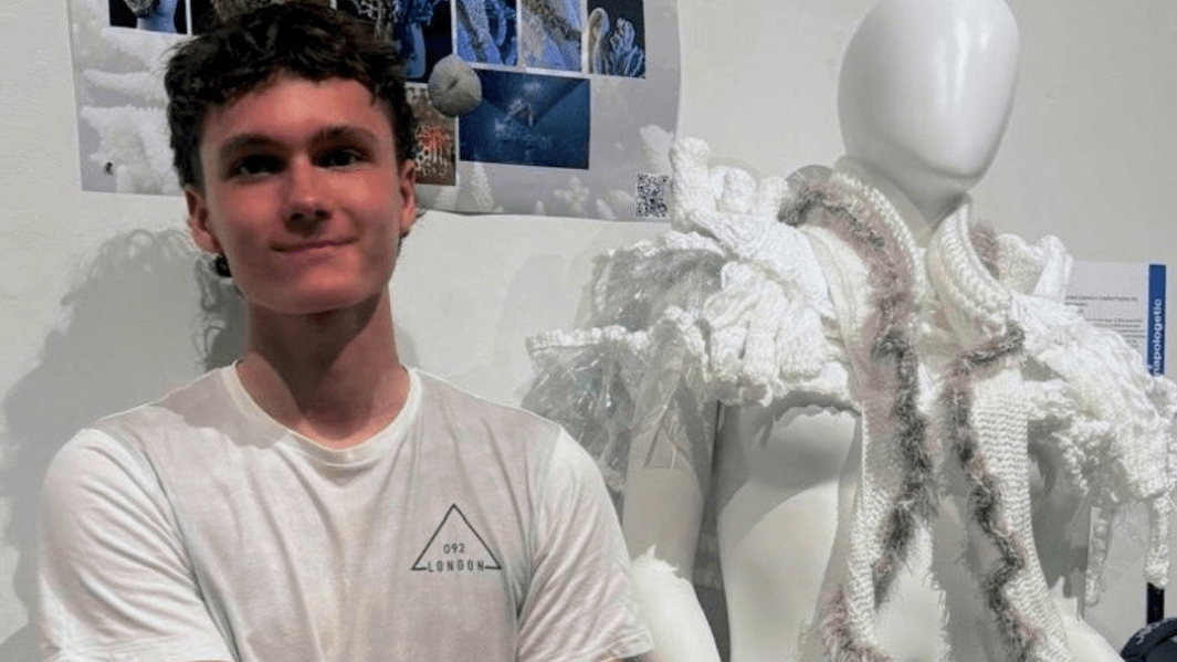 student stood next to his work looking proud