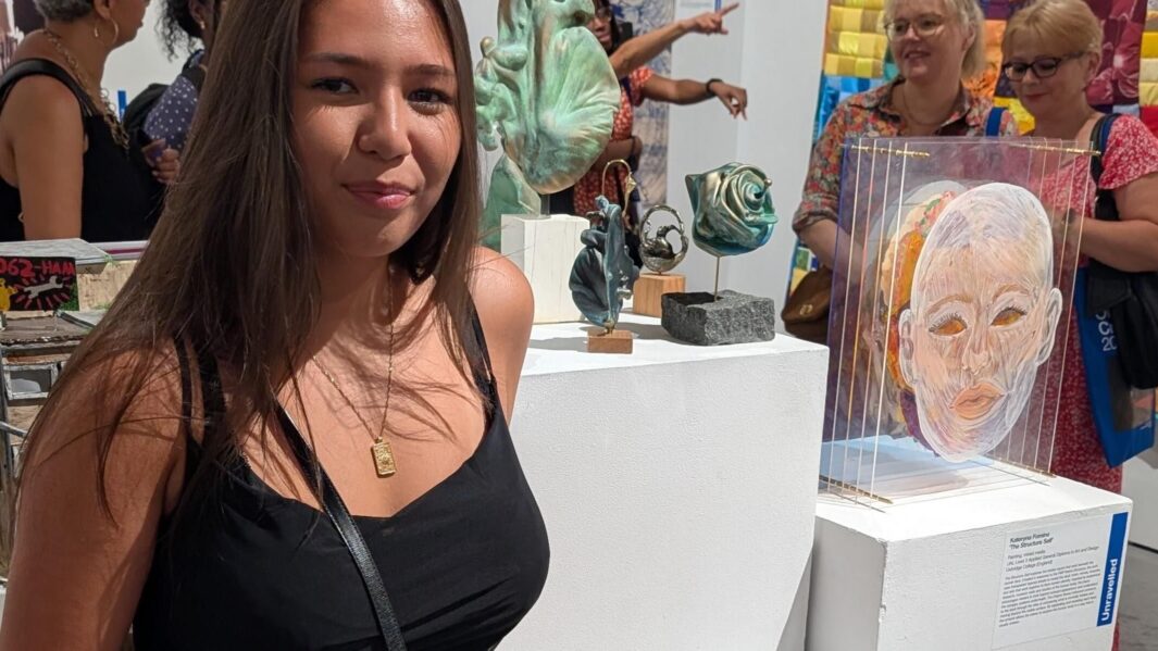 student stood next to her work looking proud